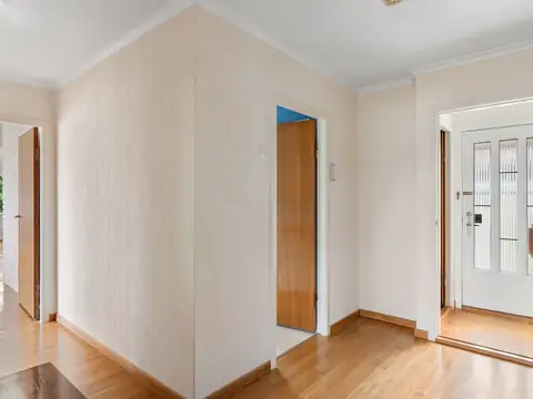 A bright, empty apartment hallway with open doors and a wood floor
