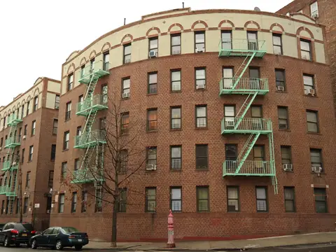 A large prewar brick apartment building with fire escapes on Sherman Avenue in the Bronx