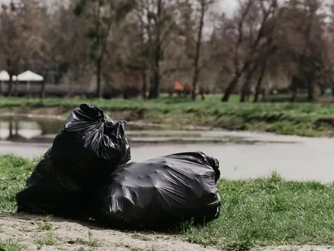 Two full black bags set out on the ground for removal