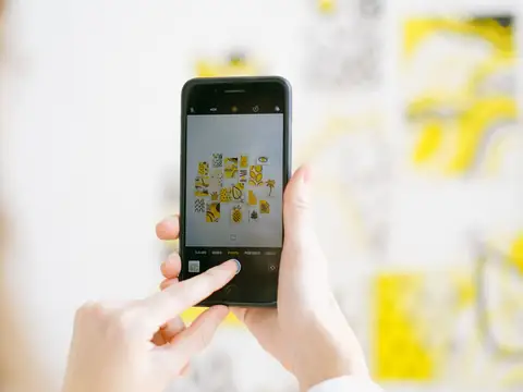 A hand holding up a phone to photograph notes on a wall