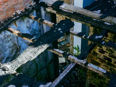 Charred, broken floor joists and boards in a burned building, seen from above
