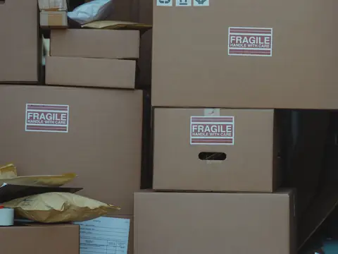 A stack of taped cardboard boxes with fragile labels