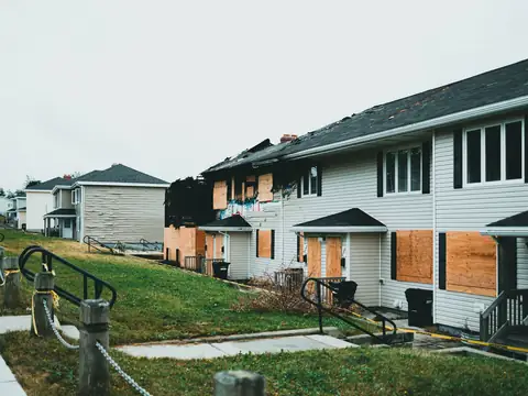 Row houses with plywood boards over the windows and doors after a fire