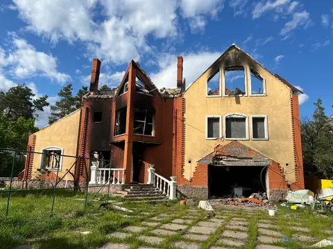 A brick house with its roof and upper floor burned away and the windows blackened