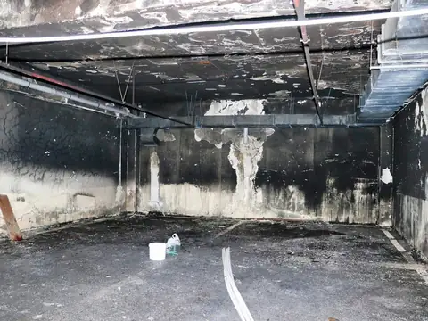 A fire-damaged room with soot-blackened walls and ceiling and a wet floor