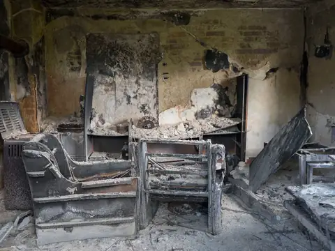Burned armchairs and soot-blackened walls in a fire-damaged living room