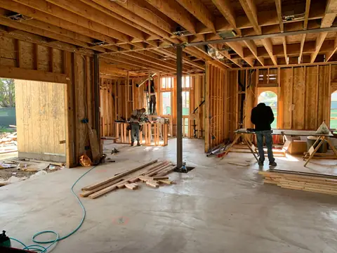 A gutted house interior with exposed wooden framing and ceiling joists during a rebuild