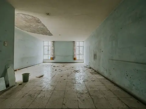A bare room with a hole in the ceiling and a stained, water-marked floor