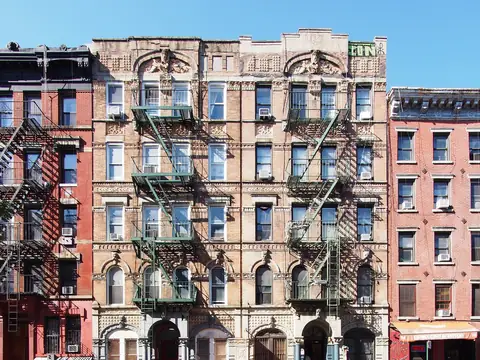 Brick walk-up buildings in Manhattan's East Village with black iron fire escapes across their fronts