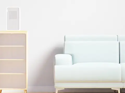 A tall air purifier beside a white sofa in a bright room