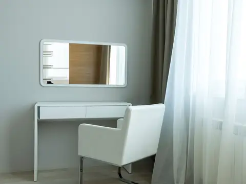 A bright, freshly finished room with white walls, a chair and sheer curtains at the window