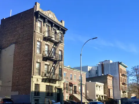 A brick apartment building with fire escapes and rows of windows on Clifton Place in Bedford-Stuyvesant, Brooklyn