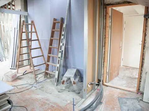 A room under renovation with ladders, bare walls and the door frames stripped back