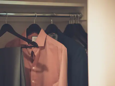 Shirts and a jacket hanging in a closet