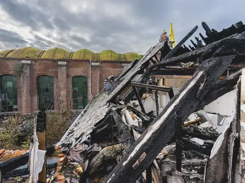 Charred roof beams and debris in the burned-out shell of a brick building